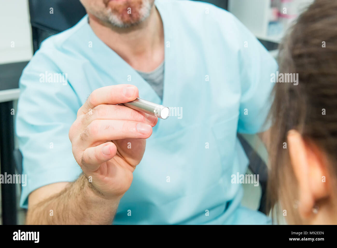 Close up médecin réflexes test de l'œil de jeune femme à l'aide d'une lampe dans une clinique médicale. L'examen physique neurologique. Focus sélectif, de l'espace pour le texte. Banque D'Images