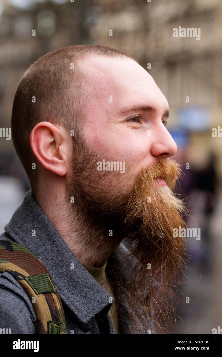Un jeune homme à la courte barbe longue et entendre s'arrête d'avoir son profil photographie prise dans le centre-ville de Dundee, Royaume-Uni. Banque D'Images