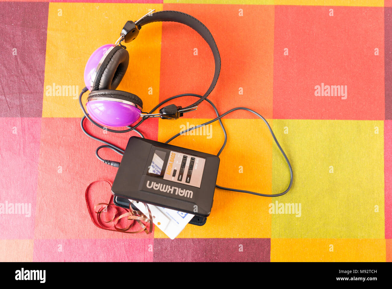 Walkman® avec une cassette à l'intérieur et les écouteurs sur une nappe à carreaux colorés. Banque D'Images