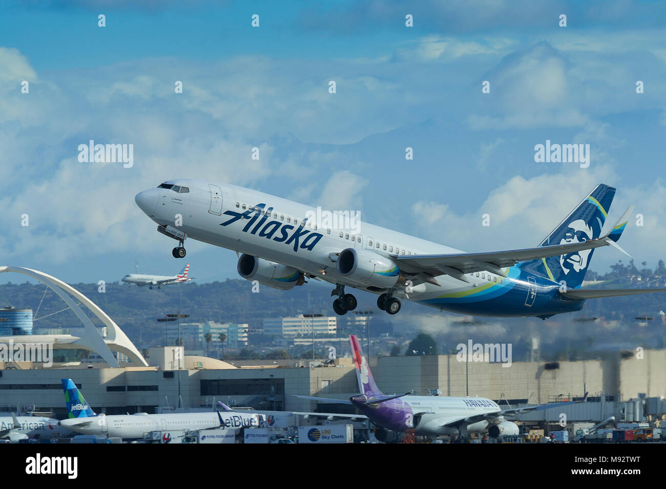 Alaska Airlines Boeing 737-800 décolle de l'Aéroport International de Los Angeles, LAX. L'atterrissage d'un avion de ligne à l'arrière-plan. Californie, USA. Banque D'Images