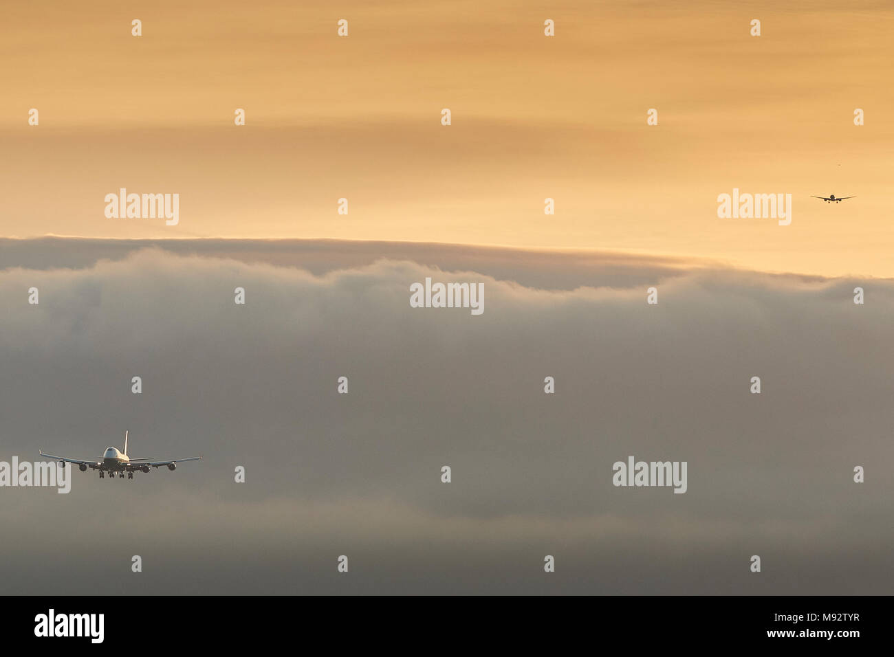 La queue des avions en approche sur l'Aéroport International de Los Angeles, LAX, au lever du soleil. D'une couche de brouillard et de nuages obscurcissant la ville et les montagnes. Banque D'Images