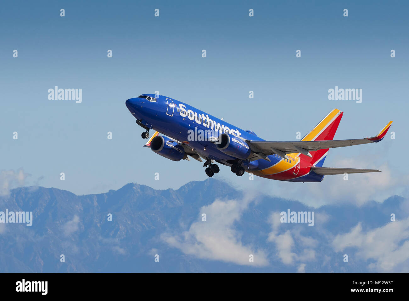 Southwest Airlines Boeing 737 avion de décoller de l'Aéroport International de Los Angeles, LAX, de nuages et de neige couverts montagnes San Gabriel derrière. Banque D'Images