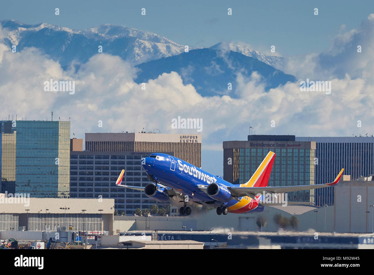 Southwest Airlines Boeing 737 avion de décoller de l'Aéroport International de Los Angeles, LAX, de nuages et de neige couverts montagnes San Gabriel derrière. Banque D'Images