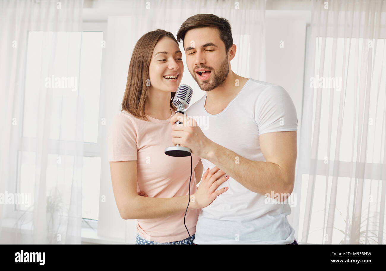 Un jeune couple avec un microphone chanter des chansons ensemble. Banque D'Images