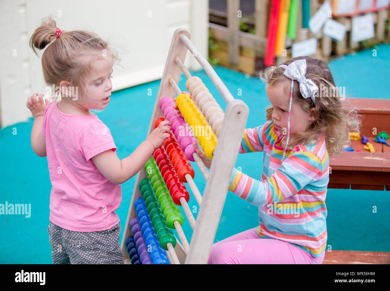 Deux jeunes filles, jouant avec un abaque à une école maternelle dans le Warwickshire, Royaume-Uni Banque D'Images