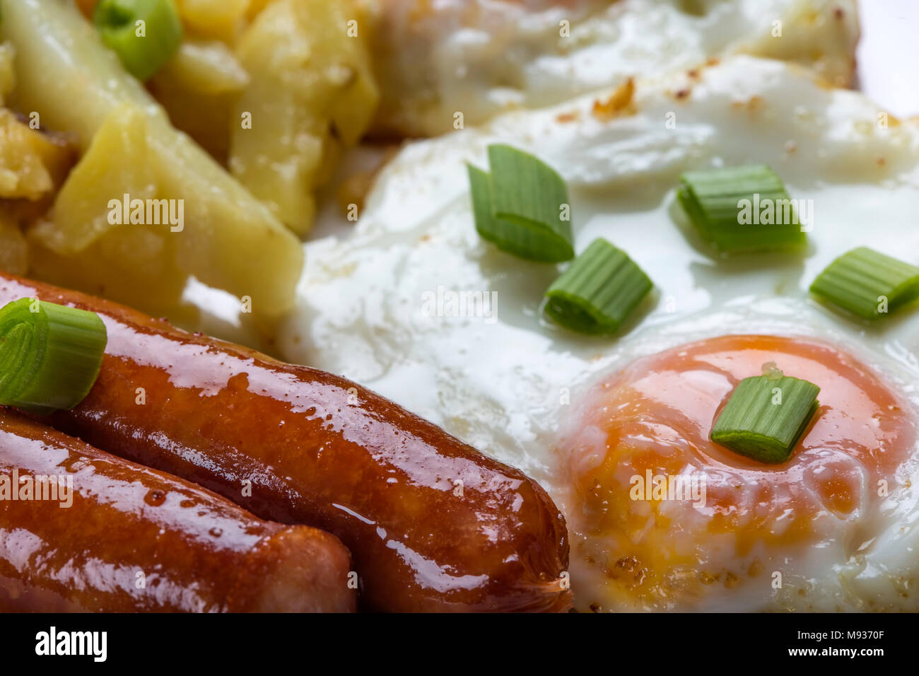 Close up d'oeufs avec frites et saucisses avec des morceaux d'oignon vert Banque D'Images