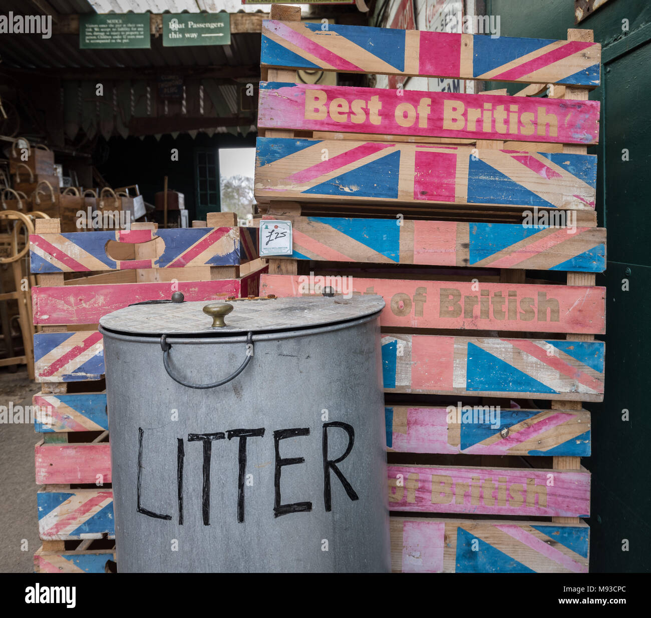 Une pile de "Best of British" caisses de légumes en bois debout à côté d'une corbeille métallique. Glastonbury, Somerset. Banque D'Images