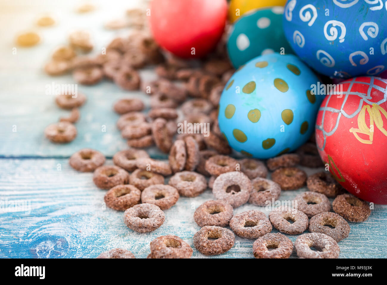 Les oeufs de Pâques colorés et anneaux de maïs doux sur fond de bois. Joyeuses Pâques Banque D'Images