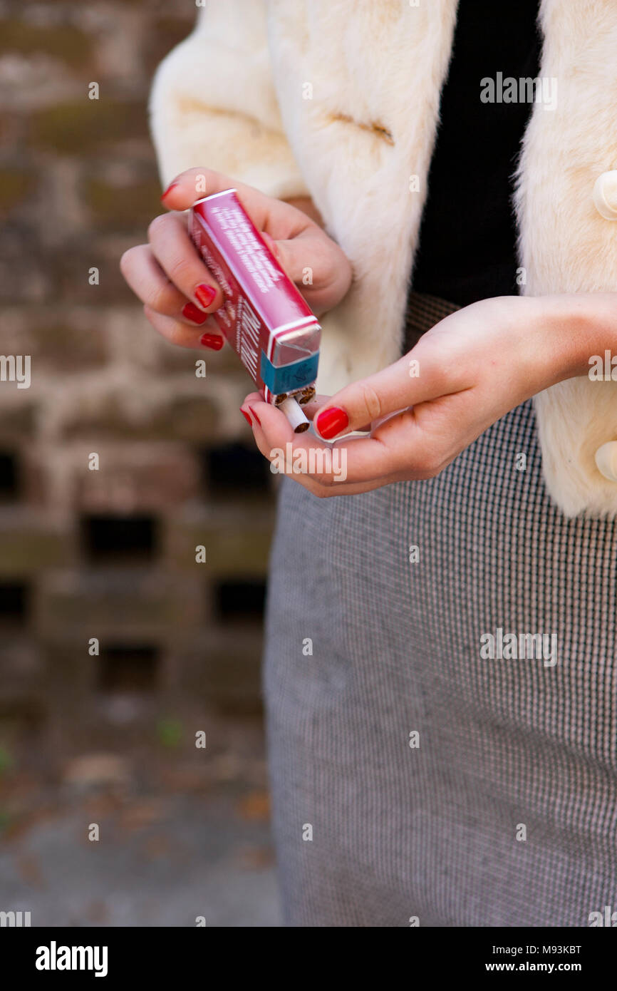 Une femme tirant une cigarette sans filtre Pall Mall) de l'emballage Photo  Stock