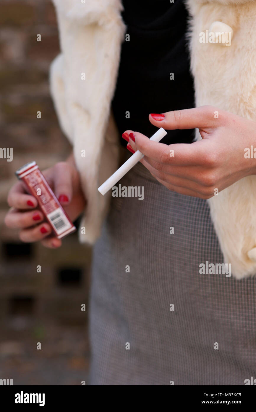 Une femme tenant une cigarette sans filtre Pall Mall. Banque D'Images