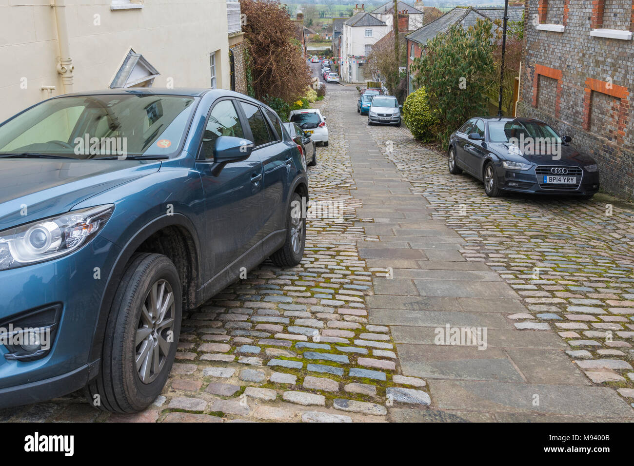 Voitures garées sur Kings Arms Hill, une ancienne route pavée sur une colline escarpée dans le marché de la ville historique sur Arundel, West Sussex, Angleterre, Royaume-Uni. Banque D'Images