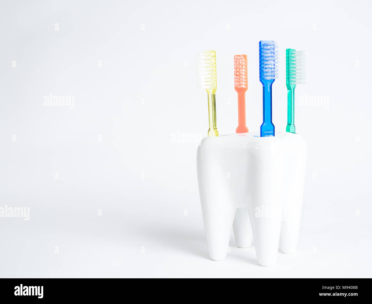 4 brosses à dents brosse à dents colorés dans une tasse une forme a une molaire Banque D'Images
