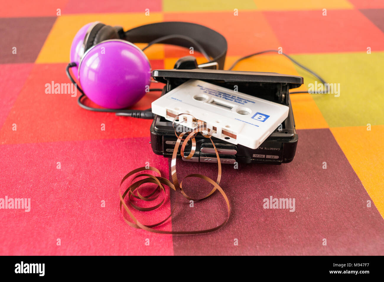 Walkman® avec une cassette à l'intérieur et les écouteurs sur une nappe à carreaux colorés. Banque D'Images