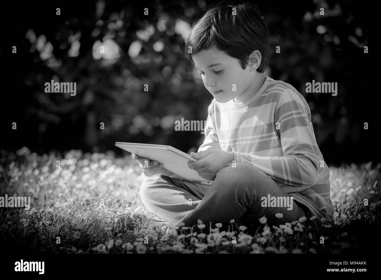 Enfant de lire un livre assis sur l'herbe Banque D'Images