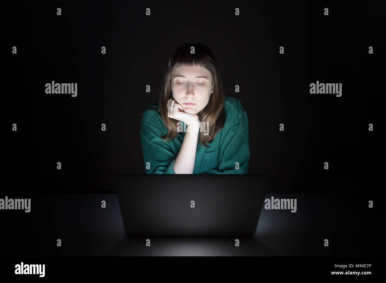 Femme à l'intérieur de l'ordinateur portable à la fin de la soirée. Portrait de jeune femme étudiant ou travailleur assis en face de l'écran de l'ordinateur pendant la nuit et de lire Banque D'Images