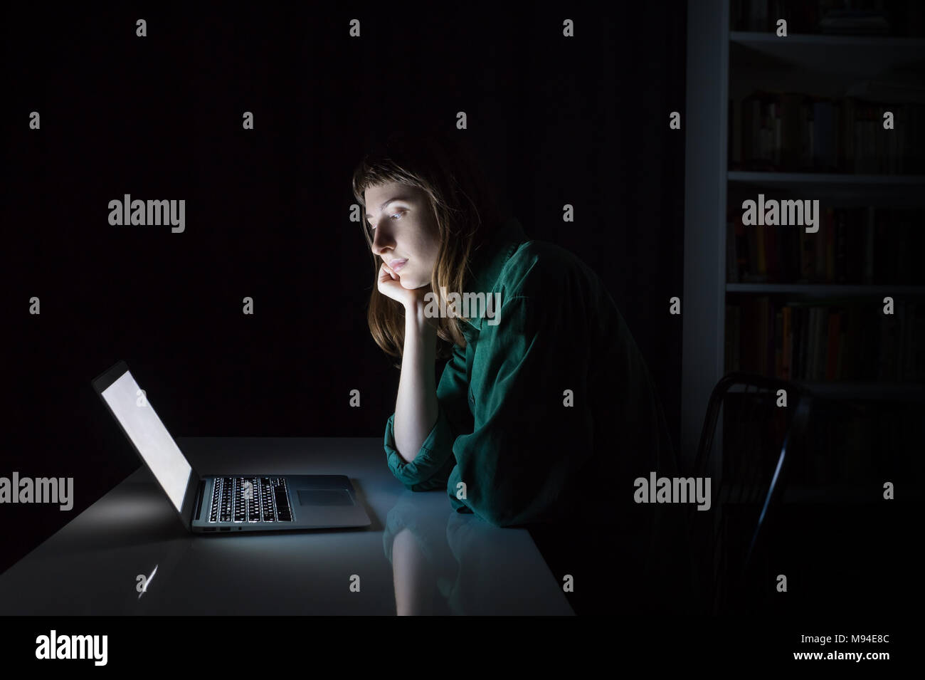 Woman at laptop computer tard dans la soirée s'ennuie ou lecture. Portrait de jeune femme étudiant ou travailleur assis en face de l'écran de l'ordinateur pendant la nuit Banque D'Images