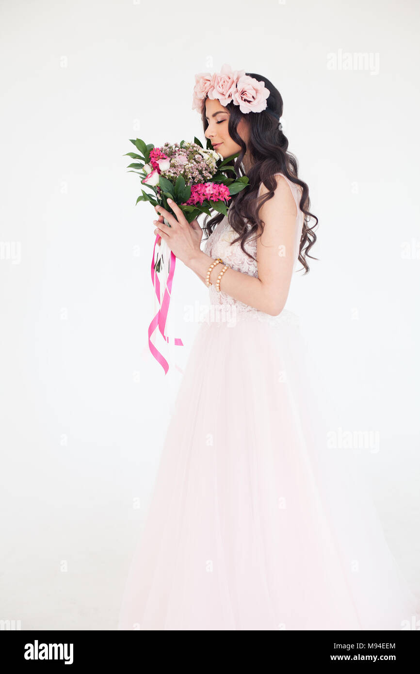 Belle jeune femme en robe rose. Modèle de mode avec des fleurs et des couronnes de fleurs rose Banque D'Images