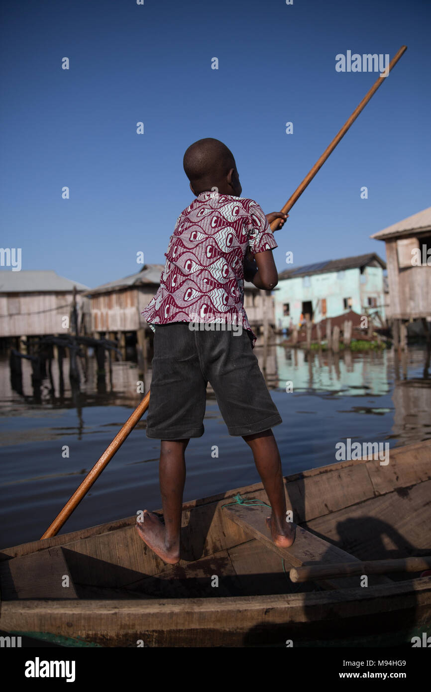 Un jeune résidant de Ganvie, dans le Lac Nokoué, pagaies son bateau par village. Ganvie est probablement le plus grand "tilt" village de l'Afrique, avec une population d'environ 20 000 personnes. Le sud du Bénin. Banque D'Images