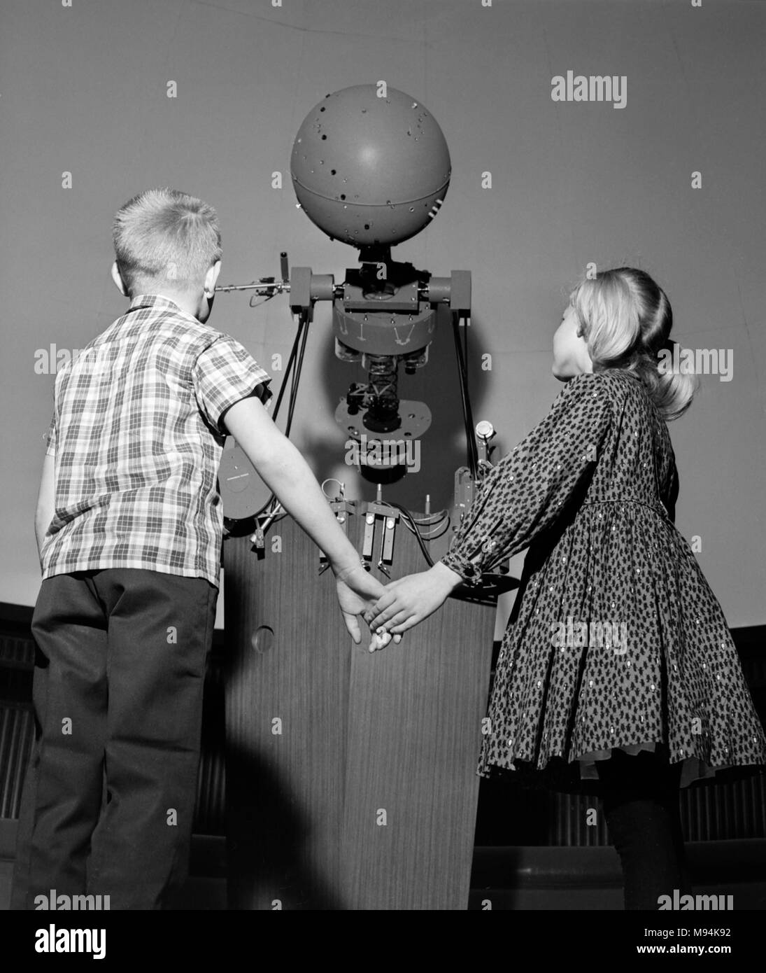 Deux enfants d'âge scolaire porte sur un planétarium projecteur pendant que sur un champ de la science voyage en Californie, ca. 1966. Banque D'Images