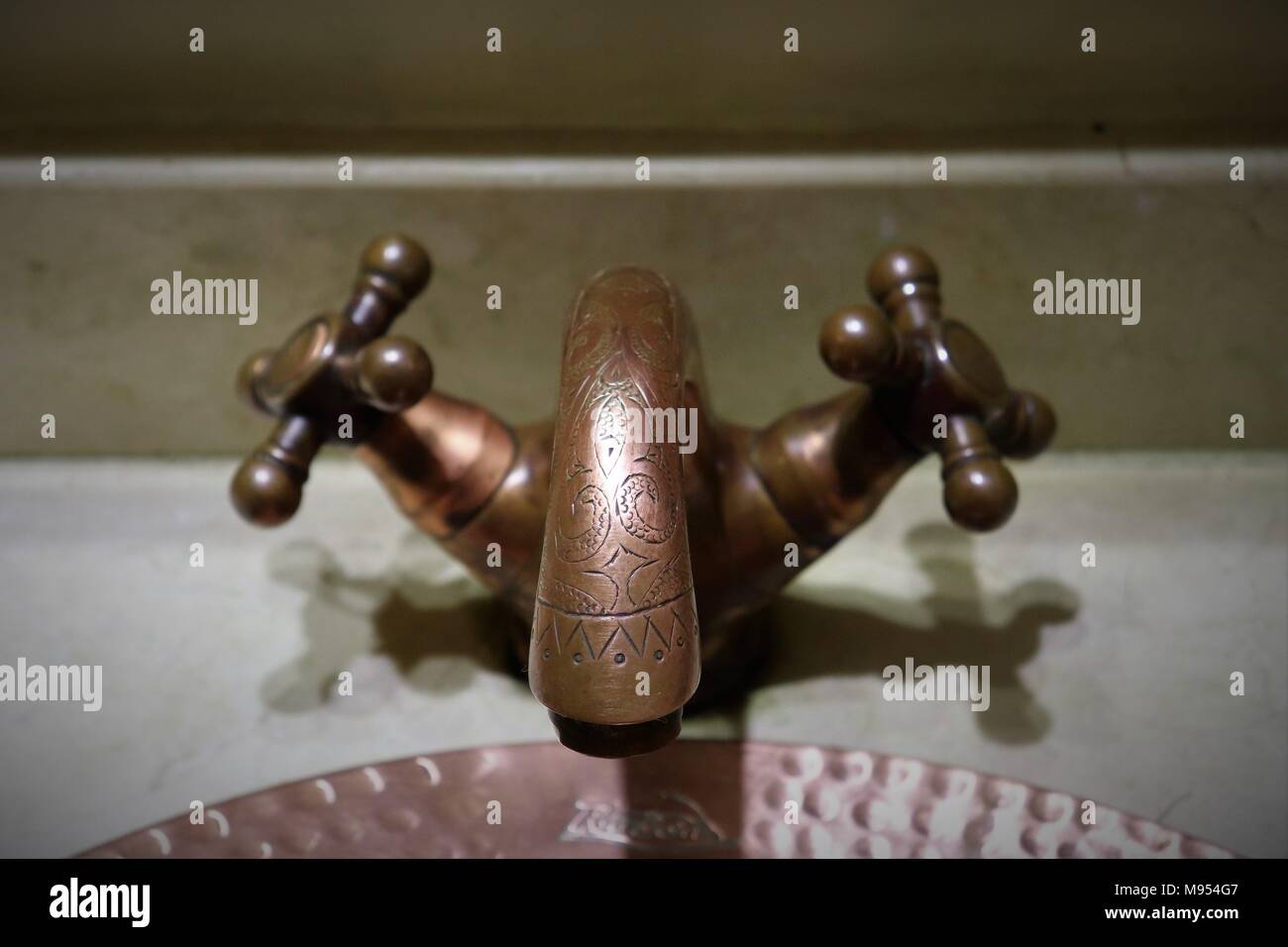 Un robinet en cuivre décoratif dans la salle de bains d'un Riad au Maroc Banque D'Images