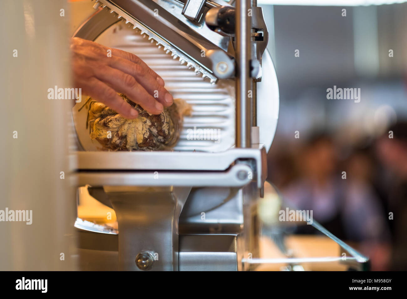 Main de boucherie charcuterie coupe dans un slicer afin de les vendre Banque D'Images