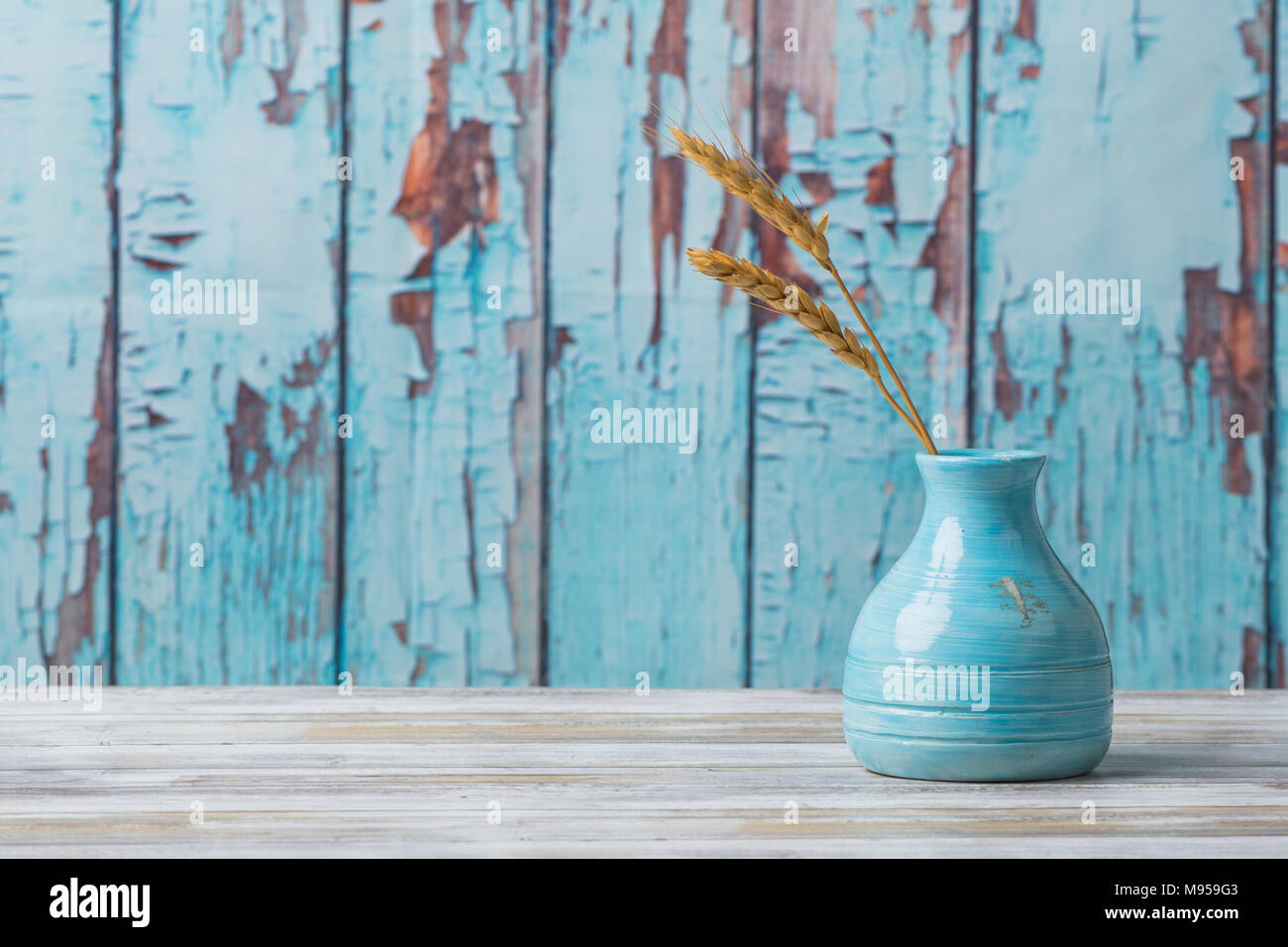 Vase poterie bleu avec des tiges de blé et de bois contexte Banque D'Images