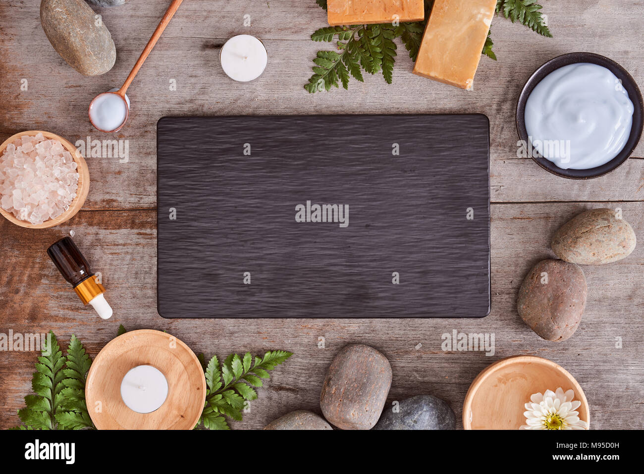 Les échantillons de produits de beauté et de sels de bain avec feuilles et pierre noire sur table en bois Banque D'Images