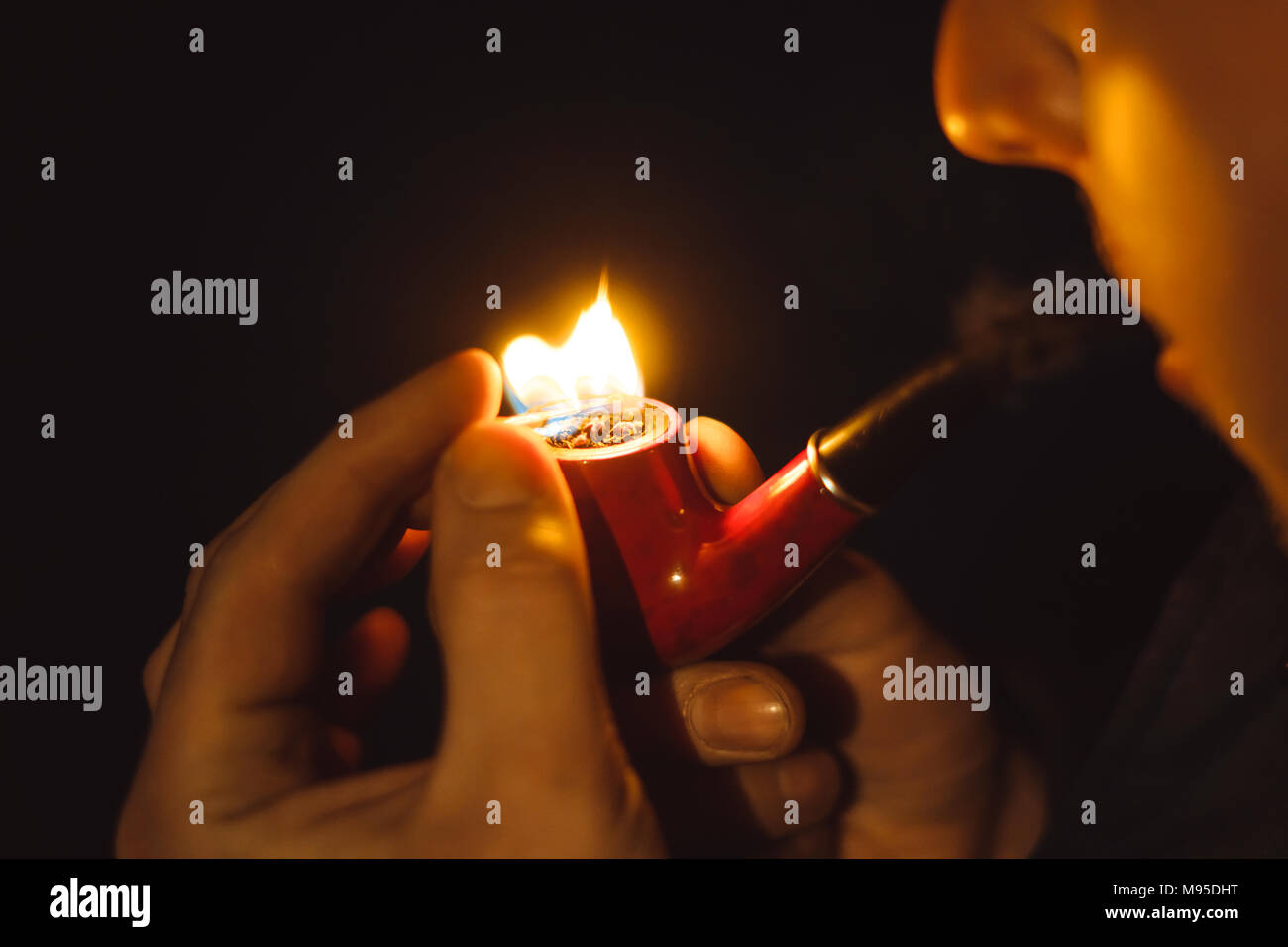 Man Smoking pipe dans la nuit à la lumière d'une lanterne Banque D'Images