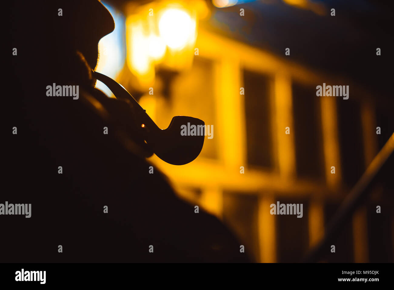 Man Smoking pipe dans la nuit à la lumière d'une lanterne Banque D'Images