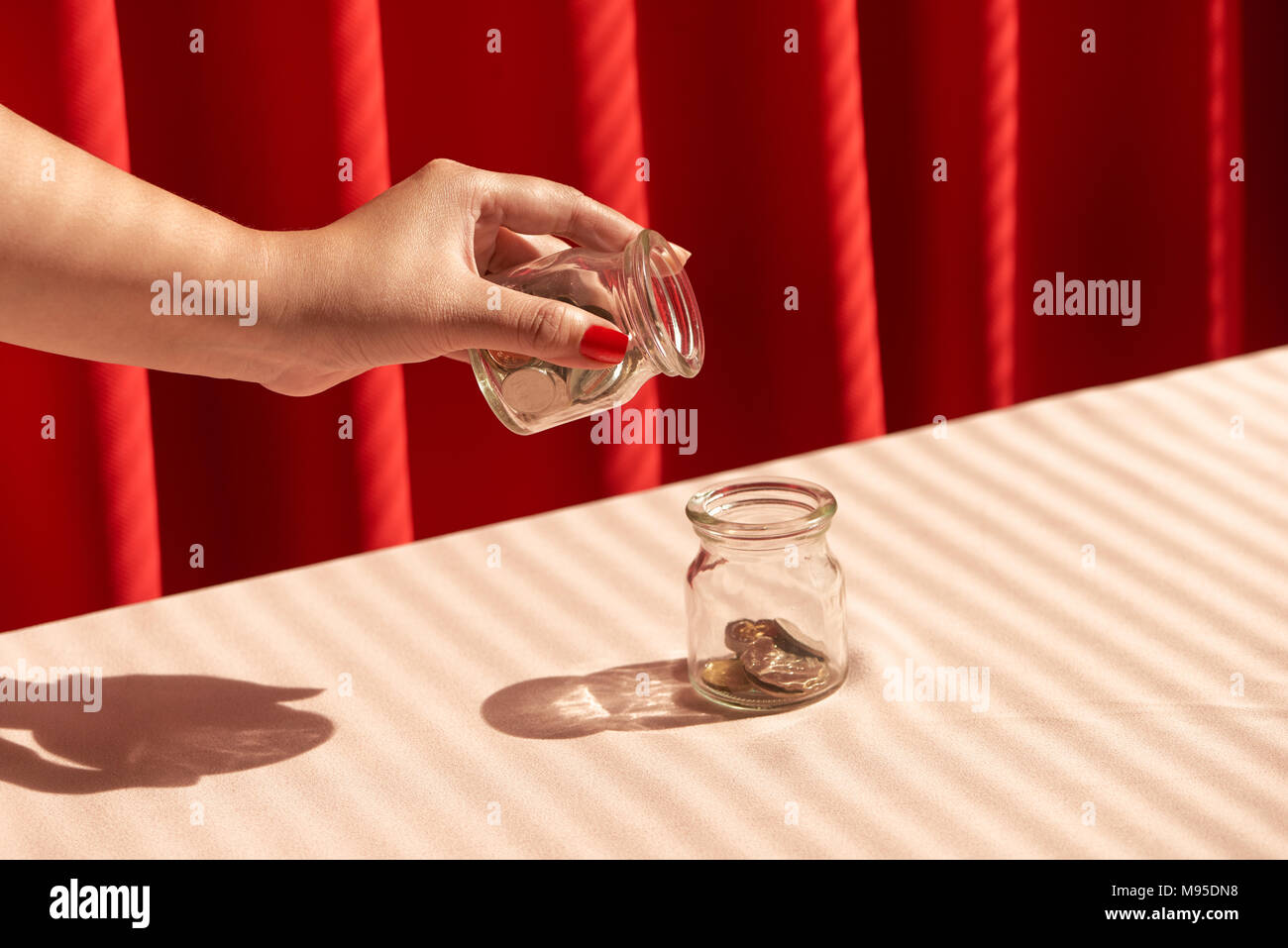 Une femme prise d'une pièce de monnaie et la mettre dans un bocal en verre Banque D'Images