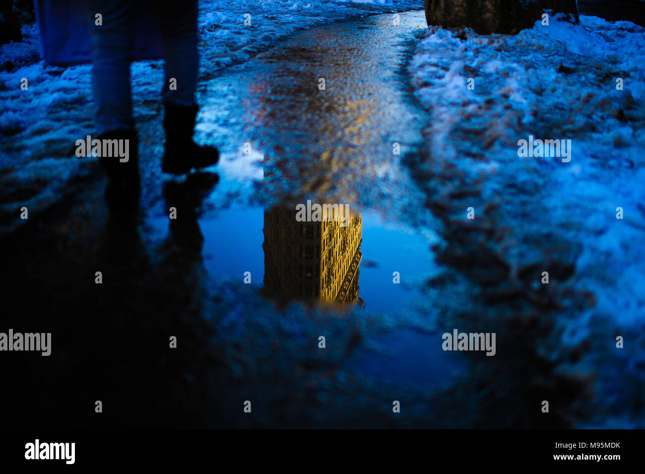 L'emblématique Flatiron Building vue reflétée dans une flaque d'eau au coucher du soleil à New York, Février 2013 Banque D'Images