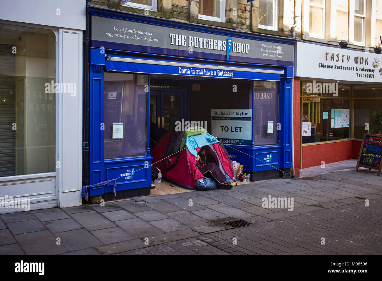 Un sans-abri et une femme vivant dans une petite tente à l'extérieur une ancienne boucherie boutique dans le centre de Lancaster, Lancashire Banque D'Images