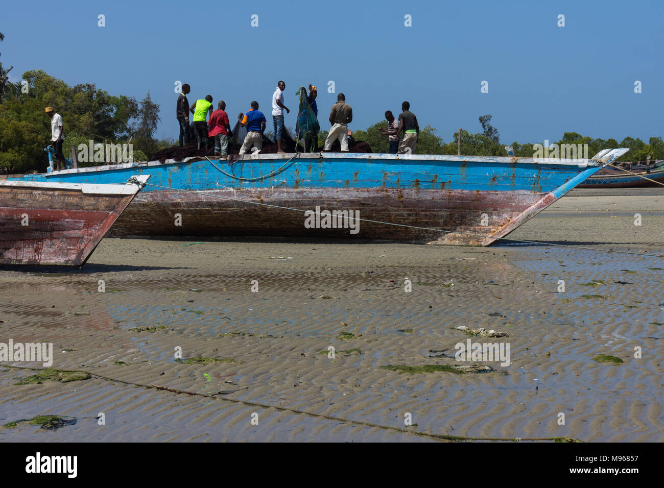Les pêcheurs travaillent dans un bateau échoué sur le sable à Zanzibar Banque D'Images