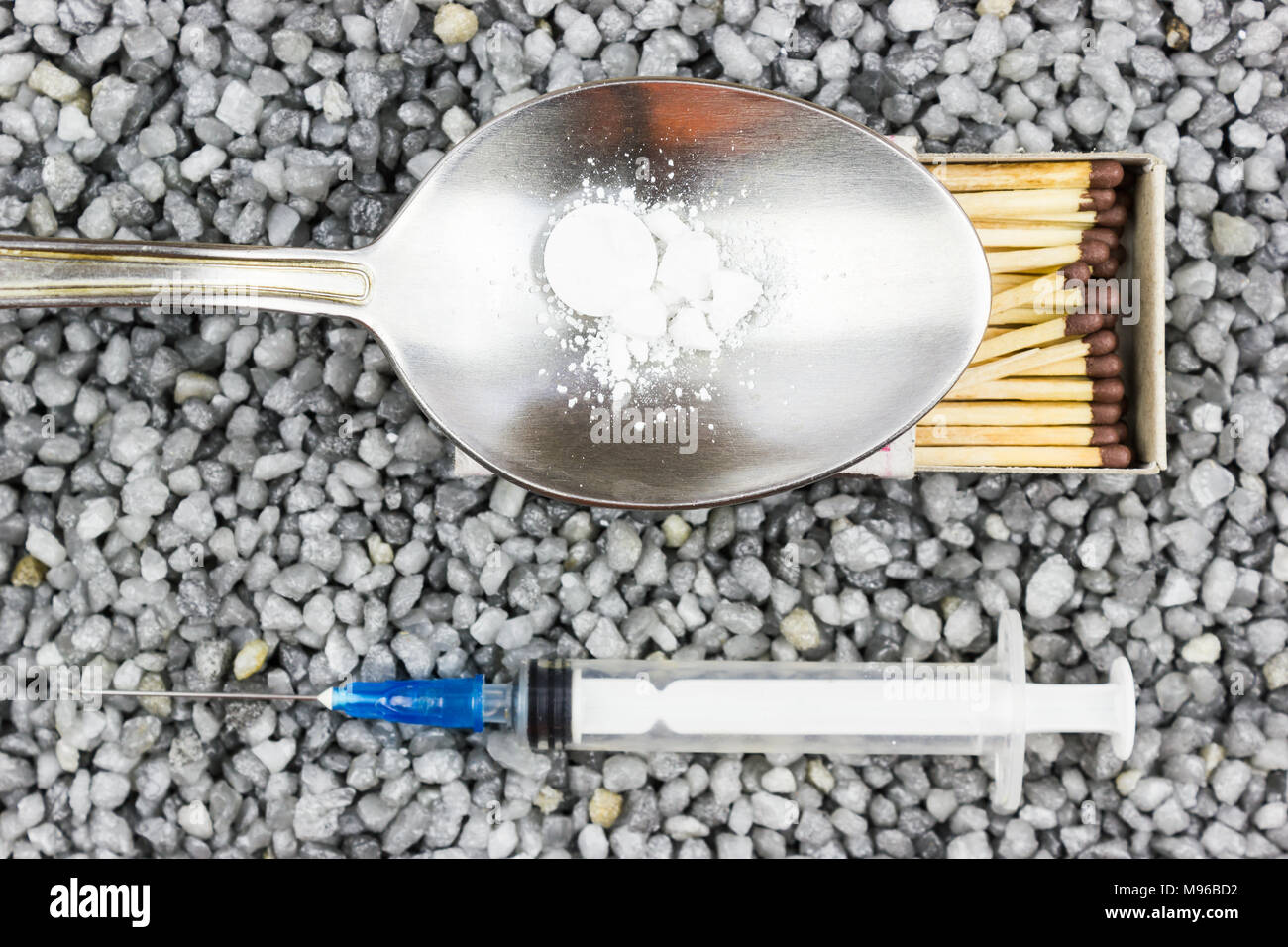 Seringue en plastique, une cuillère et un match sur le gravier fin. La médecine, la médecine. Prendre de la drogue. Banque D'Images
