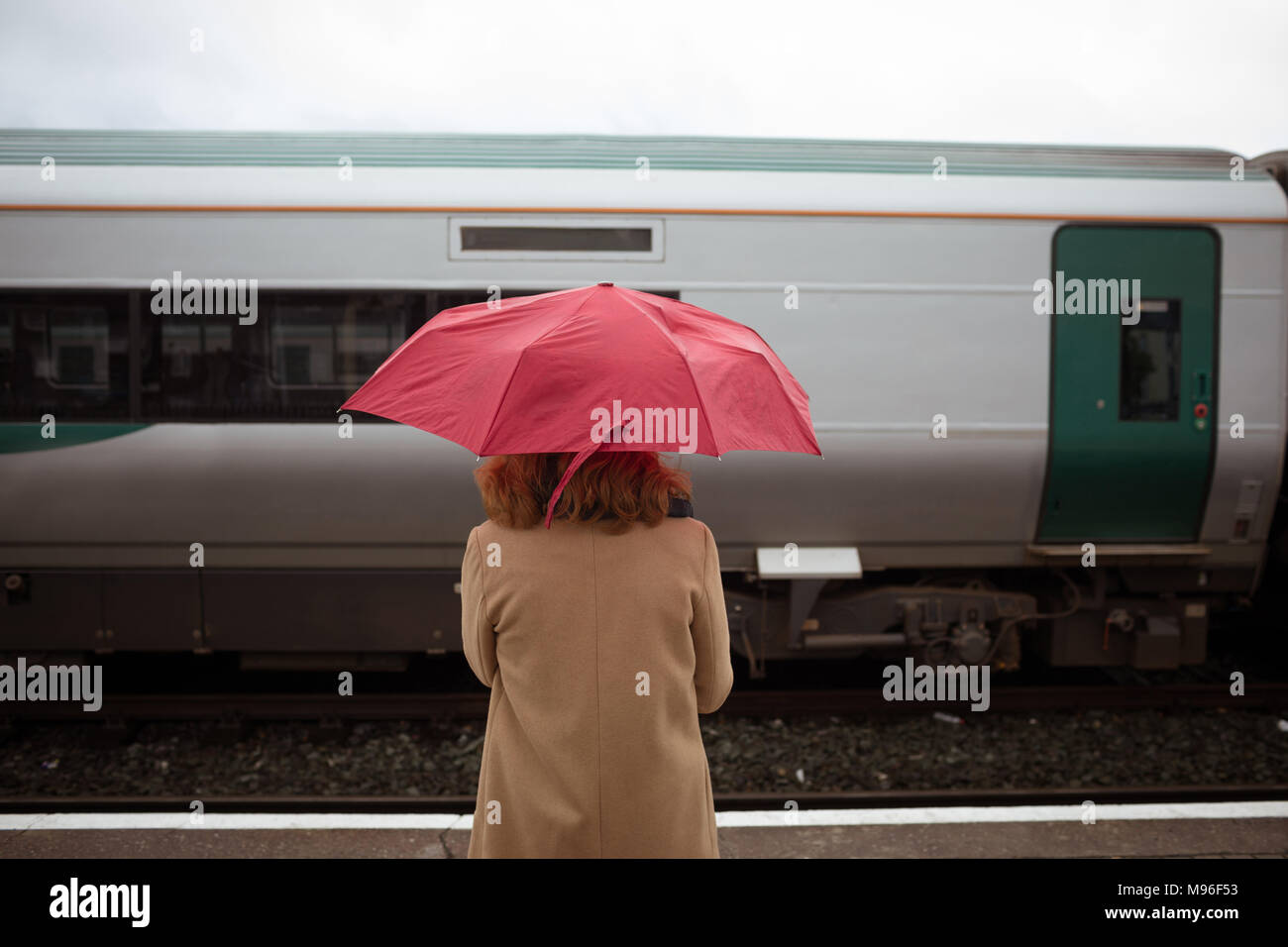 Belle jeune femme avec parapluie en attente de train sur la plate-forme Banque D'Images