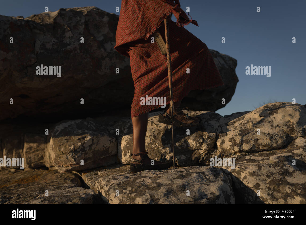L'homme en costume traditionnel masaï walking on rock Banque D'Images