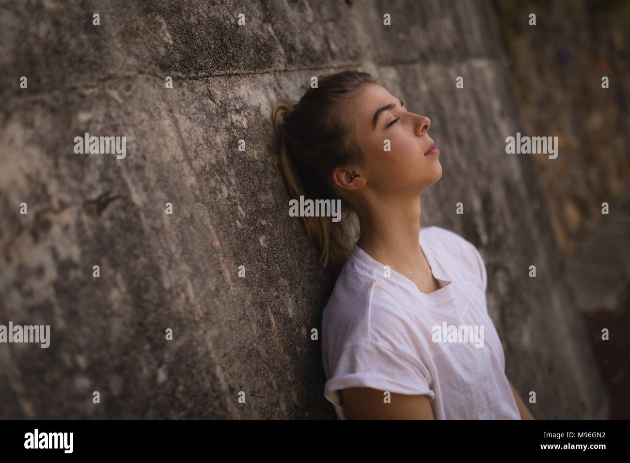 Woman leaning against wall dans la cour de tennis Banque D'Images