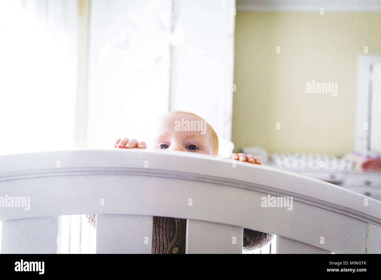 Baby peering over bed Banque D'Images