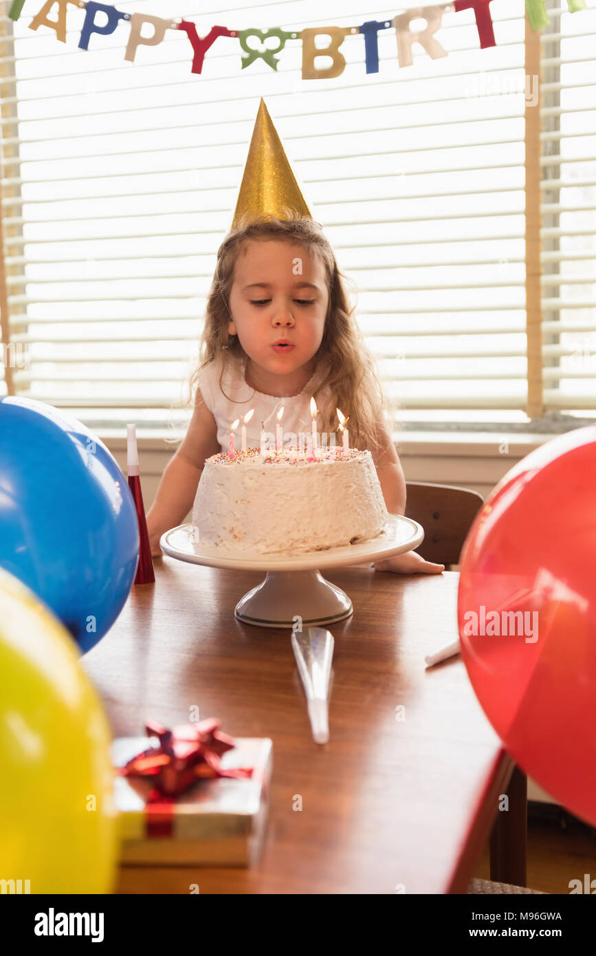 Petite fille soufflant les bougies sur son gâteau d'anniversaire Banque D'Images