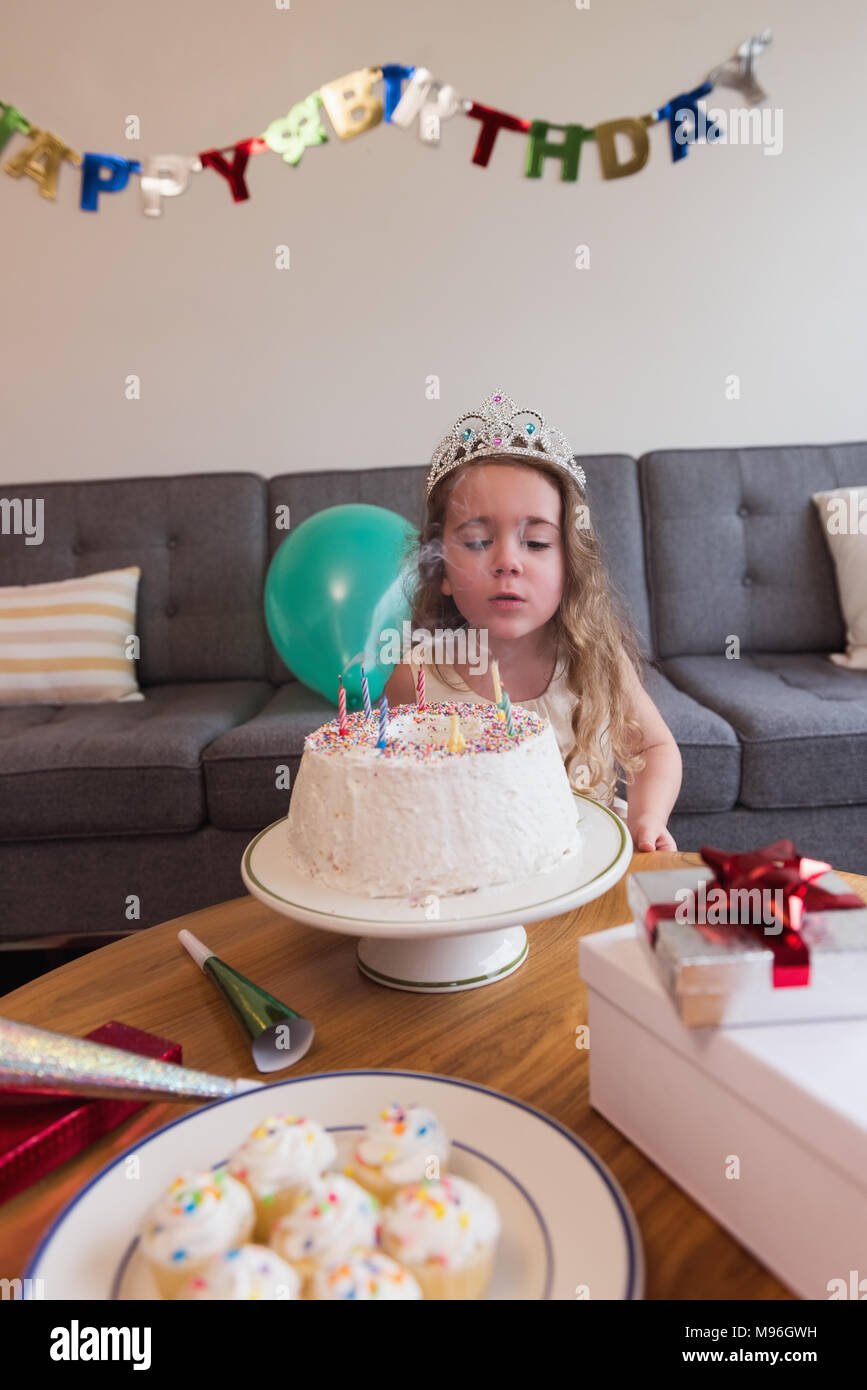 Petite fille soufflant les bougies sur son gâteau d'anniversaire Banque D'Images