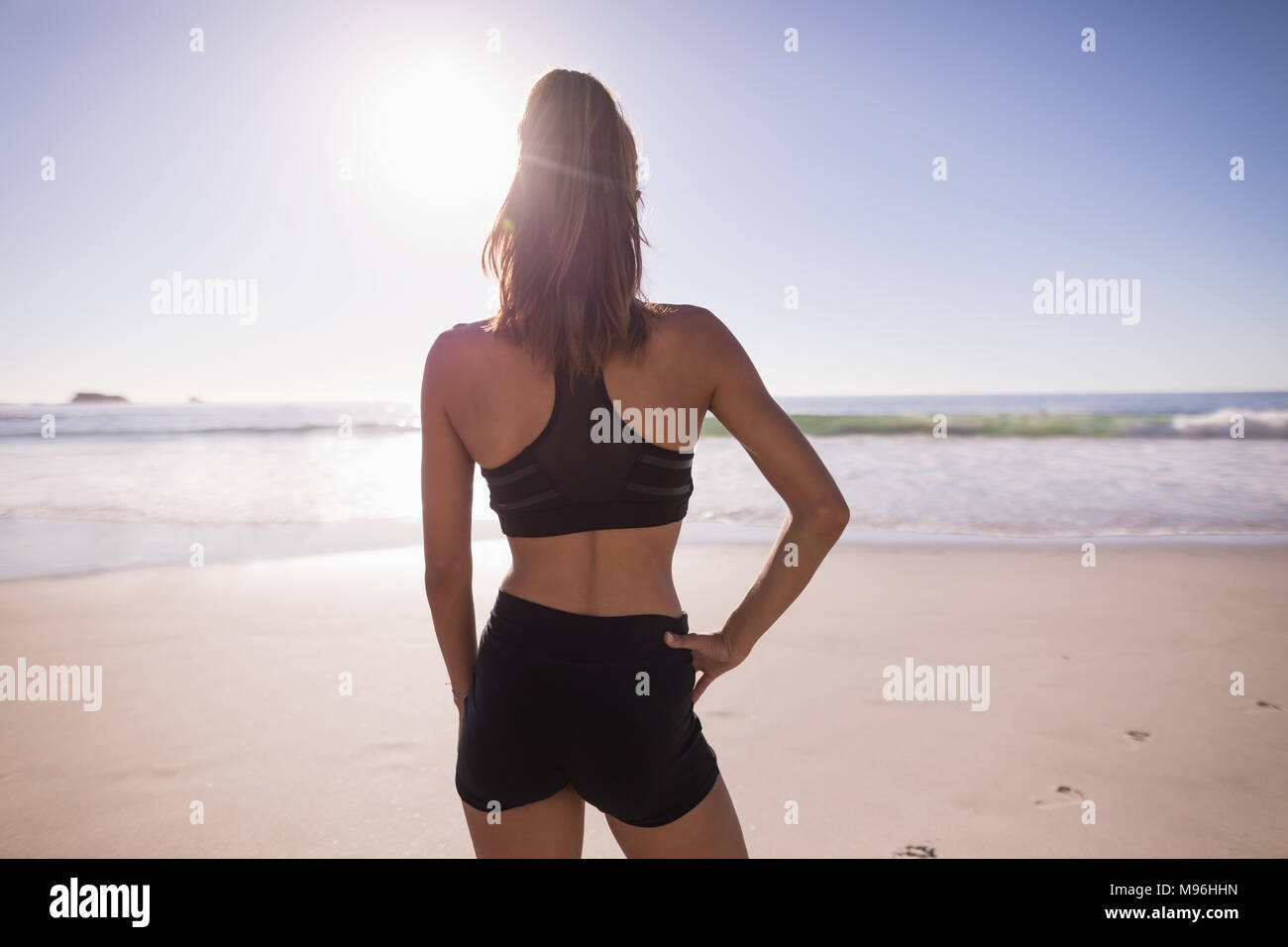 Fit woman standing with hand on hip dans la plage Banque D'Images