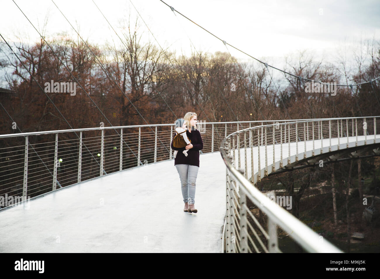 Femme tenant un enfant sur un pont métallique Banque D'Images