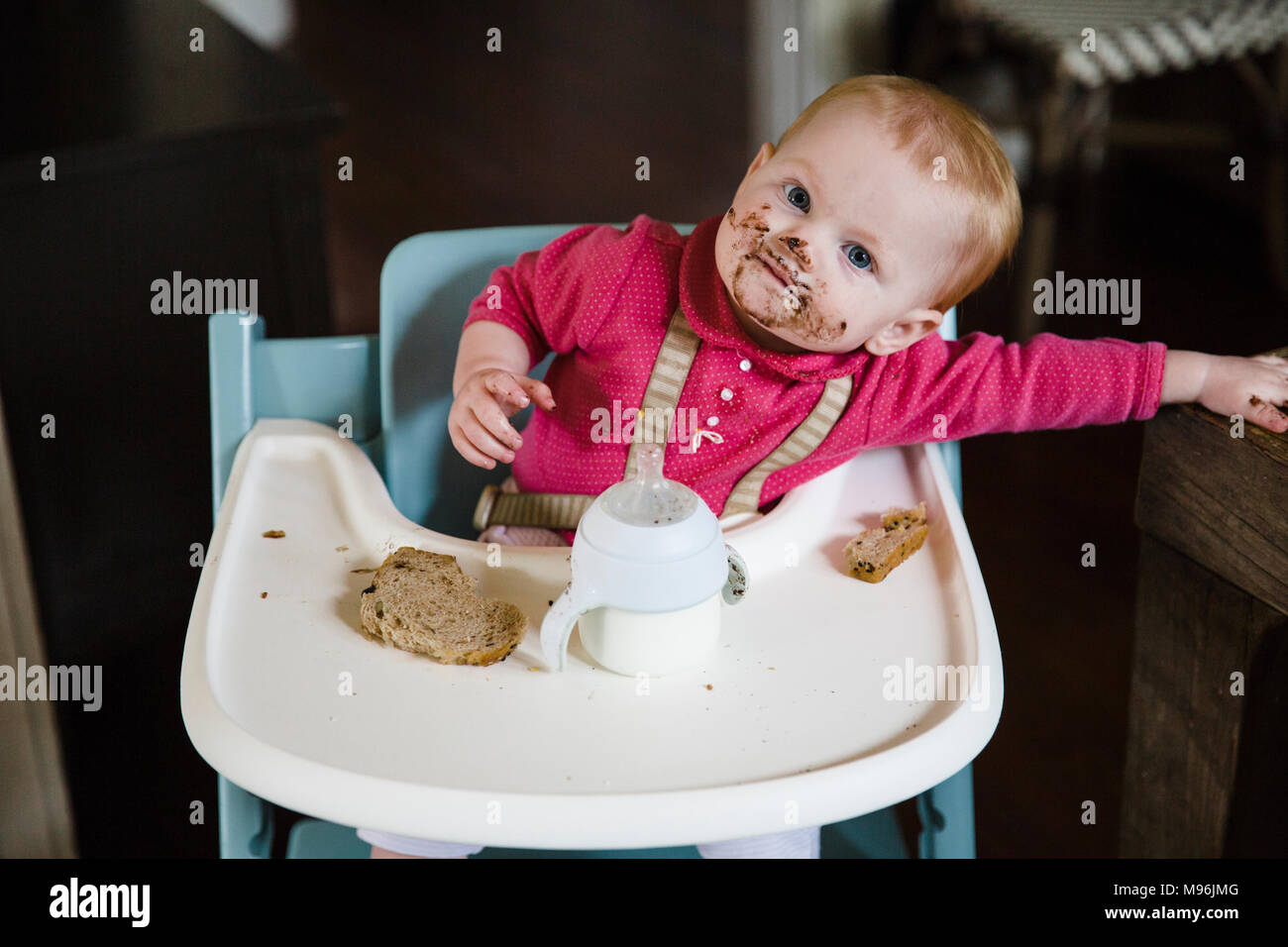 Bébé dans une chaise haute avec repas manger visage malpropre Banque D'Images