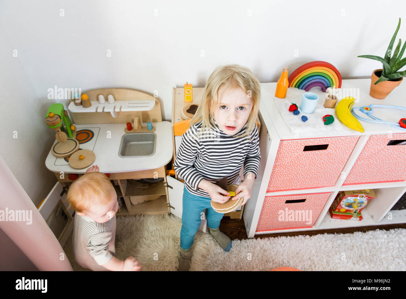 Girl looking up at camera avec bébé à côté d'elle Banque D'Images