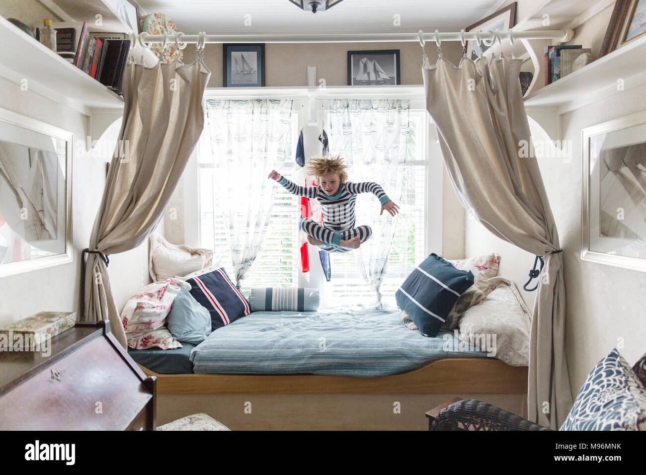 Boy jumping on bed Banque D'Images