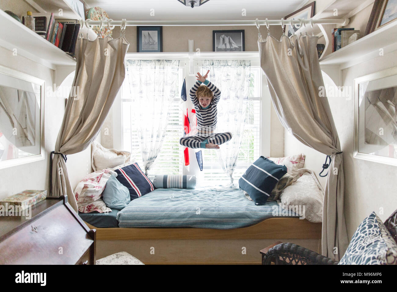 Boy jumping on bed Banque D'Images