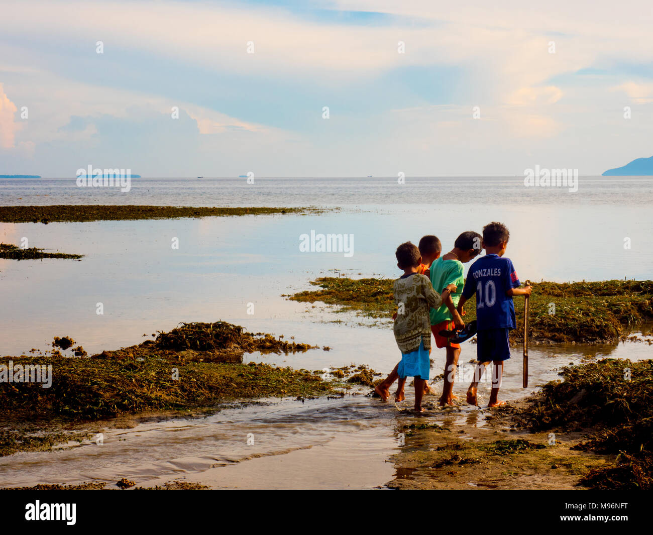 Maumere, l'île de Flores, en Indonésie - Janvier 2018 : Groupe d'enfants autochtones d'Asie non identifiés à la recherche des trésors sur la plage à marée basse. Banque D'Images Maumere, l'île de Flores, en Indonésie - Janvier 2018 : Groupe d'enfants autochtones d'Asie non identifiés à la recherche des trésors sur la plage à marée basse. Banque D'Images