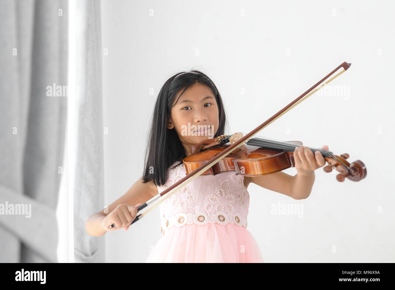 Cute girl playing violin fenêtre près de chez vous Banque D'Images