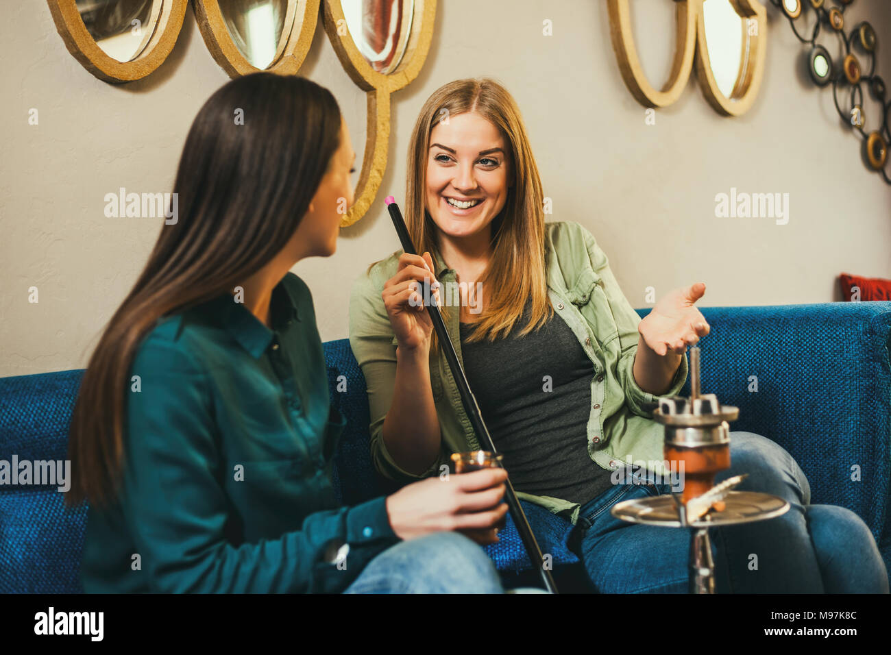 Deux heureux les femmes sont assis dans un bar à chicha et narguilé fumer Banque D'Images