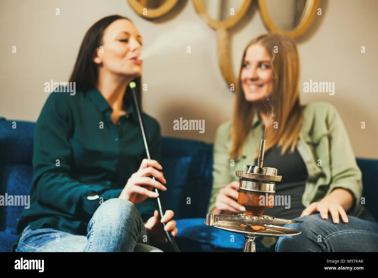 Deux heureux les femmes sont assis dans un bar à chicha et narguilé fumer Banque D'Images